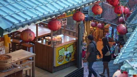 People-navigating-through-the-labyrinth-of-narrow-streets-and-steep-staircases,-exploring-the-charming-Jiufen-mountain-village-town-with-shops-and-food-stalls-along-the-way