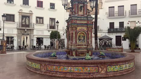 The-Pescaito-Fountain-at-Plaza-de-España,-the-bustling-hub-of-Vejer-de-la-Frontera-in-Cadiz,-Andalusia,-Spain,-fills-the-area-with-an-infectious-energy-reminiscent-of-a-vibrant-amusement-park