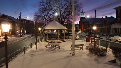 Town-square-center-covered-in-snow-during-winter-sunset,-dusk