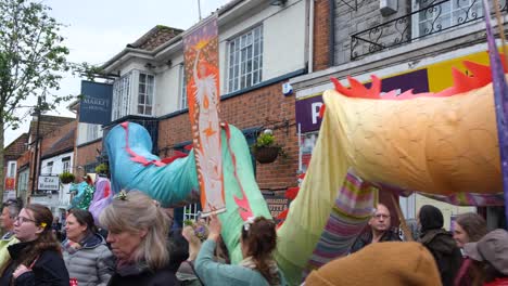 Dragón-Colorido-Moviéndose-Por-Las-Concurridas-Calles-De-La-Ciudad-De-Glastonbury-Durante-El-Día-De-Mayo-De-Beltane,-Principios-De-Verano,-Celebraciones-Y-Festivales-En-Somerset,-Reino-Unido