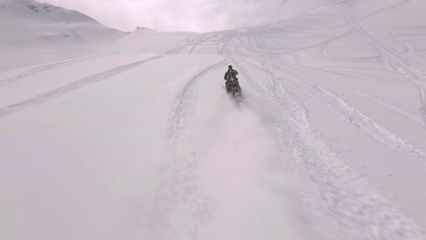 Aerial-FPV-Following-Snowmobile-Rider-Across-Snow-Covered-Sharkstooth-Peak-Landscape-Doing-Wheelie-In-Colorado