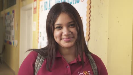 Retrato-De-Una-Joven-Estudiante-Latina-Sonriendo-A-La-Cámara-En-La-Escuela-Del-área-Urbana