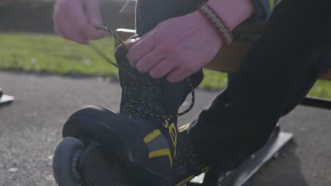 Close-up-young-man-tying-inline-roller-blade-skates-laces,-golden-hour-evening-sunset
