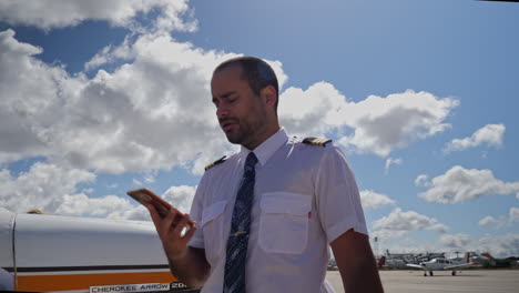 Un-Piloto-Masculino-Habla-Por-Teléfono-Cerca-De-Su-Avión-En-La-Zona-De-Plataforma