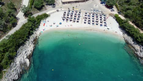 Órbita-Aérea-Sobre-La-Bahía-De-La-Playa-De-Ammoussa,-Sombrillas,-Lefkada,-Grecia