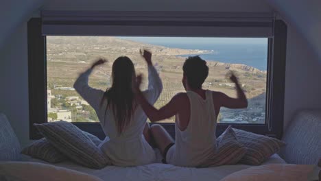 Una-Joven-Pareja-Milenaria-Celebra-La-Increíble-Vista-De-Una-Habitación-De-Hotel-En-La-Costa-Europea-De-Grecia