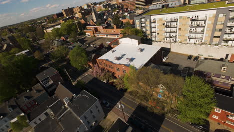 FPV-drone-flight-over-houses-and-apartment-blocks-with-green-rooftop-in-american-town-at-sunset