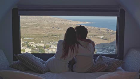 young-millenial-female-lover-embraces-boyfriend-on-romantic-night-overlooking-the-sea-in-luxury-hotel-room
