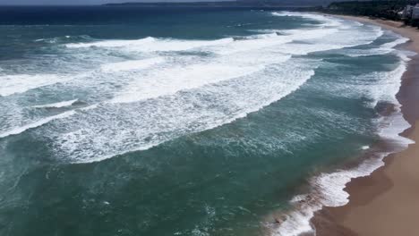 Eine-Ruhige-Küste-Mit-Wellen,-Die-Den-Goldenen-Sand-Streicheln,-Luftaufnahme