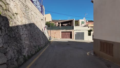 Walking-on-the-street-in-Son-Servera,-small-Mallorcan-town-in-Spain,-early-morning-sun-and-traditional-houses