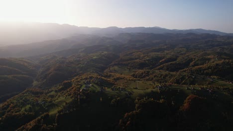 Pestera-village-in-brasov-at-sunset-with-rolling-hills-and-scattered-houses,-aerial-view