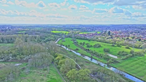 Eine-Ruhige-Frühlingslandschaft-Außerhalb-Von-Leicester,-Großbritannien:-Ein-Wanderweg-Verläuft-Entlang-Des-Ruhigen-Flusses,-Während-Sonnenstrahlen-Die-Grünen-Wiesen-Erhellen