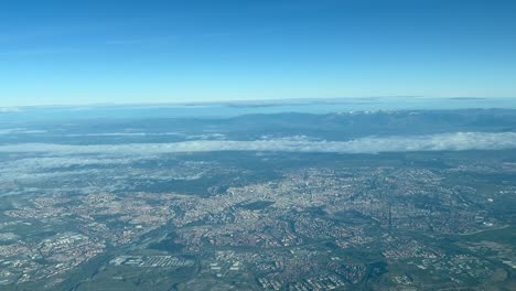 Vista-Aérea-Desde-La-Cabina-De-Un-Avión-De-La-Ciudad-De-Madrid,-España,-Saliendo-Del-Aeropuerto,-Con-Algunas-Nubes-En-El-Cielo-Y-Montañas-Nevadas