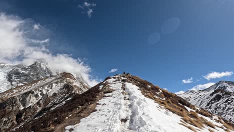 An-adventurous-hike-on-the-snow-covered-trails-heading-to-the-summit-of-Kyanjin-Ri,-with-the-stunning-backdrop-of-Langtang-Lirung’s-mountain-massif-and-deep-blue-skies-in-Nepa