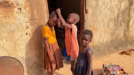 three-children-black-african-standing-together-in-remote-village-while-comb-curl-hair