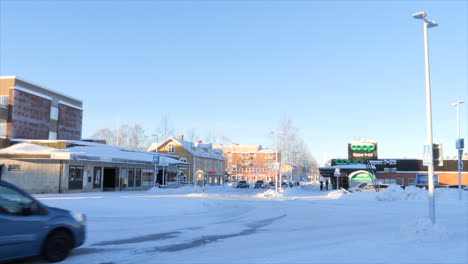 Vehicles-Driving-On-Snowy-Street-In-Arvidsjaur,-Sweden-On-Winter-Day