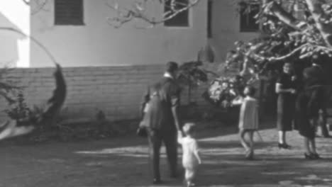 Mann-Geht-Mit-Kleinen-Kindern-Im-Garten-Eines-Eleganten-Hauses-Aus-Den-1930er-Jahren-Spazieren