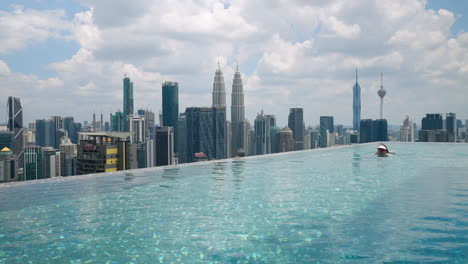 Frau-Schwimmt-Auf-Dem-Dach-Eines-Luxushotels-Mit-Infinity-Pool-In-Der-Stadt-Kuala-Lumpur,-Malaysia
