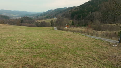 Malerischen-Grünen-Grashügel-Mit-Blick-Auf-Ländliche-Landstraße-Unterhalb-Bewaldeten-Berg