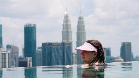 Mujer-En-La-Piscina-Infinita-De-La-Azotea-Con-Las-Torres-Gemelas-Petronas-Al-Fondo-En-Kuala-Lumpur,-Malasia