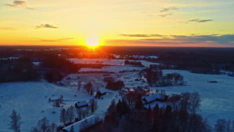 Snowy-countryside-village-at-sunset-in-winter---sliding-aerial-view