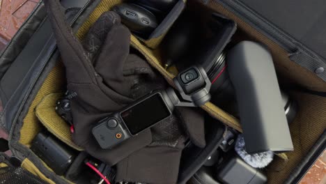 Rotating-top-down-view-of-camera-bag-full-of-photography-equipment-with-Osmo-Pocket