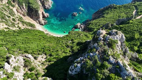 Aerial-shot-of-Giali-Beach-in-Corfu,-lush-greenery-surrounding-turquoise-waters,-sunny-day