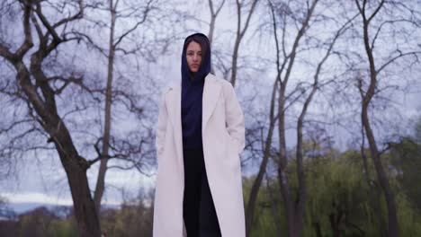 Low-angle-view-of-serious-woman-wearing-hoodie-and-long-coat-walk-by