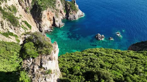 Giali-beach-on-corfu-island,-turquoise-waters-surrounded-by-lush-cliffs,-aerial-view