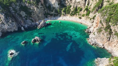 Giali-Strand-Auf-Korfu,-Griechenland-Mit-Kristallklarem-Blauem-Wasser-Und-Schroffen-Klippen,-Luftaufnahme