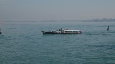 Venice-water-bus-cruising-calmly-across-serene-lagoon-waters,-showcasing-the-tranquil-daily-commute