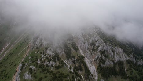 Neblige-Berge-Mit-Wolken,-Die-über-Schroffe-Klippen-Rollen,-Luftaufnahme