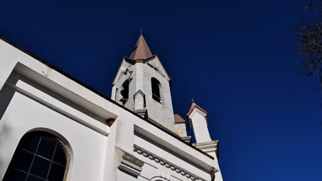 Church-steeple-in-mid-sunny-day,-renaissance-architecture-jutting-the-clear-blue-sky