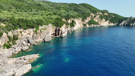 Lush-green-cliffs-overlooking-the-clear-blue-Ionian-Sea-in-Corfu,-Greece,-serene-aerial-view