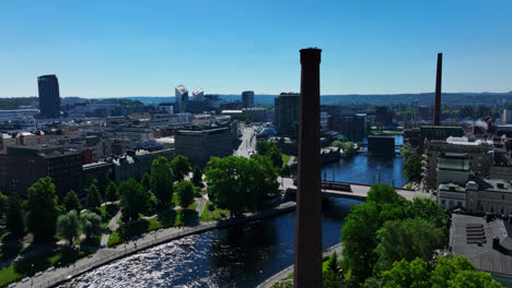 Aerial-view-following-a-tram-crossing-a-bridge,-in-downtown-Tampere,-Finland