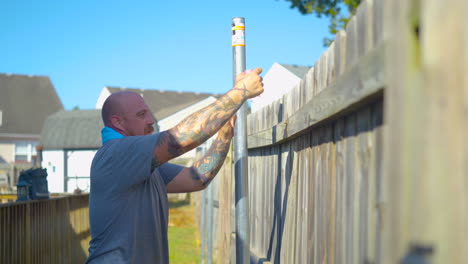 Contractor-pulling-cord-taunt-before-setting-fence-outside