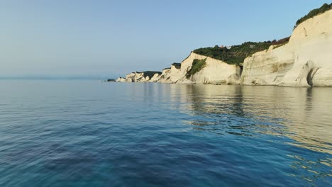 Sonnenbeschienene-Klippen-Der-Insel-Korfu-Vor-Dem-Ruhigen-Ionischen-Meer-Zur-Goldenen-Stunde,-Weitwinkelaufnahme