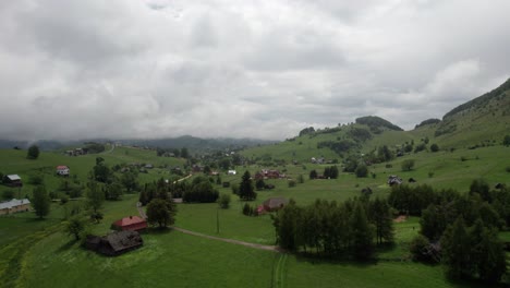 Sirnea-village-in-romania-with-green-hills-and-scattered-houses,-cloudy-day,-aerial-view