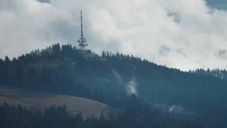 A-radiocommunication-tower-with-a-multitude-of-antennae-attached-stands-on-top-of-the-forest-covered-hill-in-the-Austrian-Alps