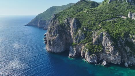 Sonnenbeschienene-Klippen-Auf-Der-Insel-Korfu-Am-Ionischen-Meer,-üppiges-Grün-An-Der-Küste,-Luftaufnahme