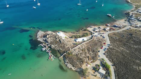 Aerial-footage-of-turquoise-waters-and-a-small-beach-club-on-the-island-of-Paros,-one-of-the-many-Cyclades-Islands-in-the-Aegean-Sea