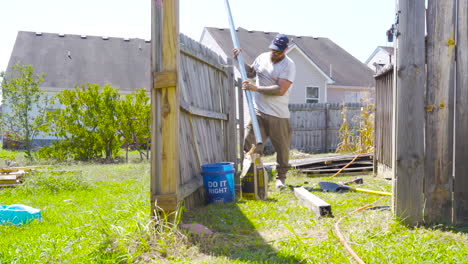 Man-sets-metal-post-in-the-ground-for-fence-repair