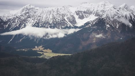 Clouds-whirl-between-snow-covered-peaks-and-gloomy-a-snowless-valley-below