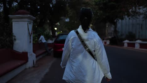 Woman-wearing-a-white-shirt-walks-down-a-busy-street-in-India