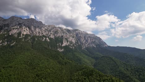 Montañas-Piatra-Craiului-Con-Exuberante-Bosque-Verde-Bajo-Un-Cielo-Azul,-Vista-Aérea