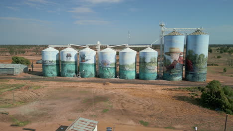 Drones-Aéreos-Vuelan-Silos-De-Grano-Con-Obras-De-Arte-Pintadas-En-Agricultura,-Campo,-Ciudad-Australiana-De-Yelarbon