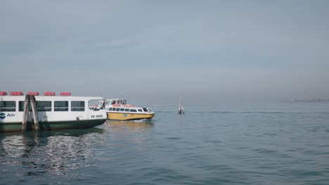 Waterbus-arrives-at-a-bustling-pier-in-Venice,-showcasing-a-vibrant-scene-against-a-serene-backdrop-of-the-Venetian-Lagoon