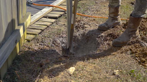 Man-uses-shovel-to-mix-concrete-around-a-post