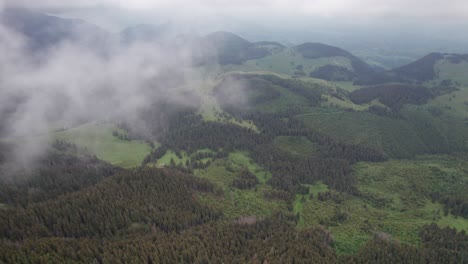 Misty-mountainous-landscape-with-dense-forest-and-clouds-at-high-altitude,-greenery-and-nature-scene,-aerial-view