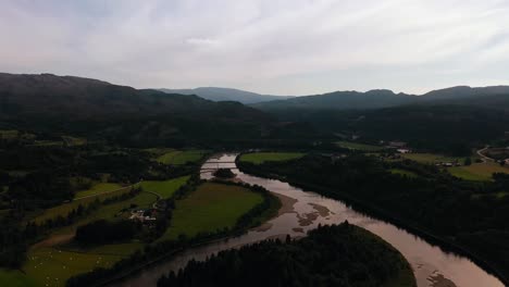 Aerial-view-backwards-over-a-river,-in-middle-of-nature-of-Central-Norway
